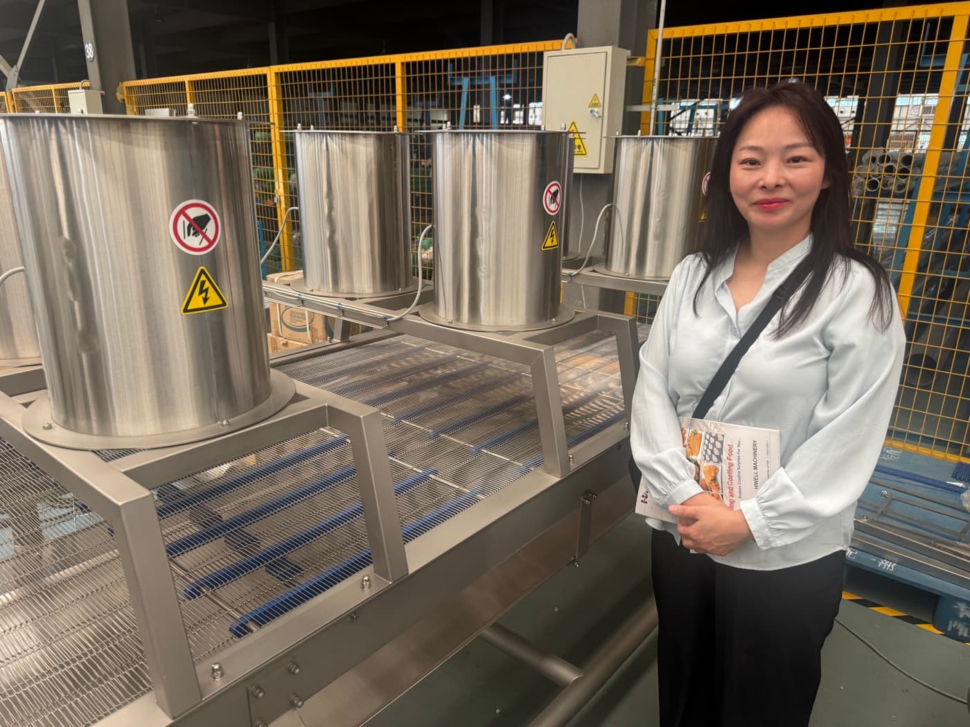 A Young Foods founder next to a coating and crumbing line at the machinery manufacturer
