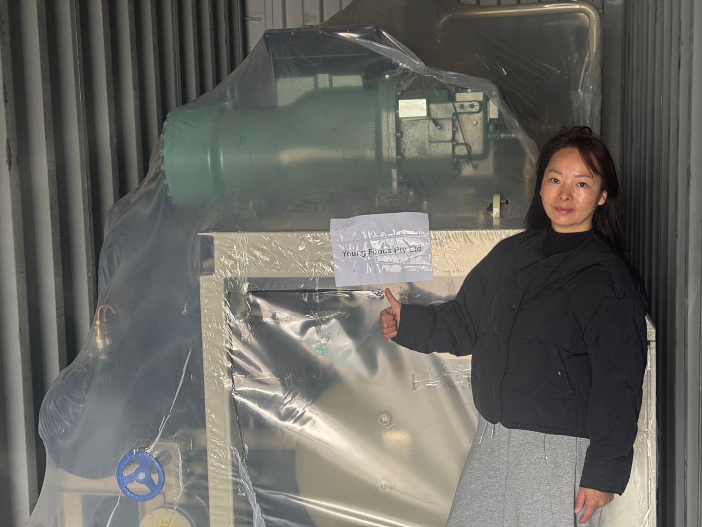 A Young Foods founder beside newly arrived equipment in a shipping container, labelled Young Foods Pty Ltd